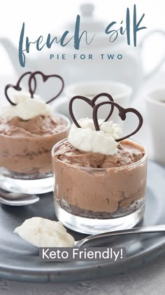 two desserts with chocolate frosting and hearts on top, sitting on a plate