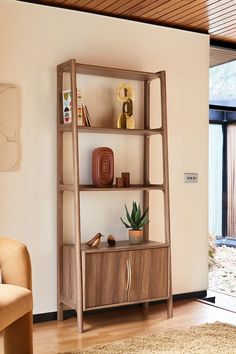 a living room with a book shelf and chair next to a sliding glass door that opens onto a patio