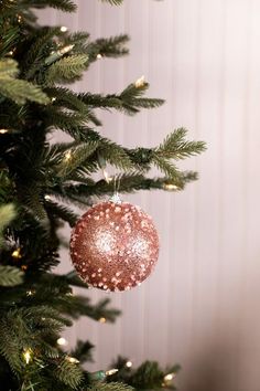 a pink ornament hanging from the top of a christmas tree