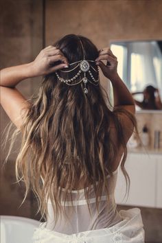 the back of a woman's head with long hair in front of a mirror