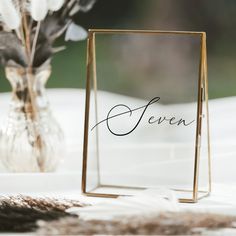 a table with a vase filled with flowers and a sign that says feven on it