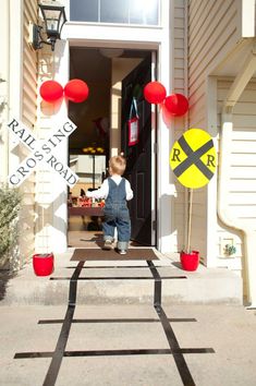 a little boy standing in front of a door with red and yellow decorations on it