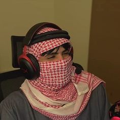 a man with headphones and a scarf around his face sitting in an office chair