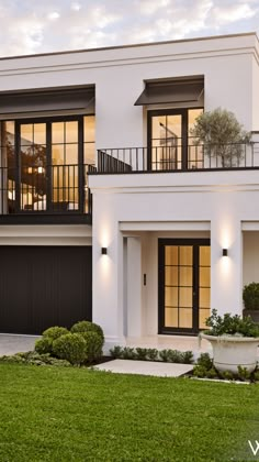 a white two story house with black windows and balconies on the second floor