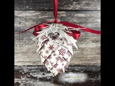 a christmas ornament hanging from a red ribbon on a wooden surface with snowflakes