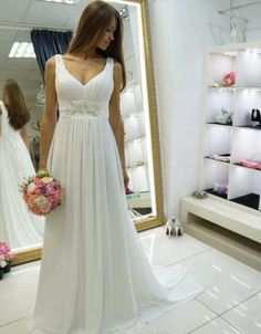 a woman standing in front of a mirror wearing a white dress