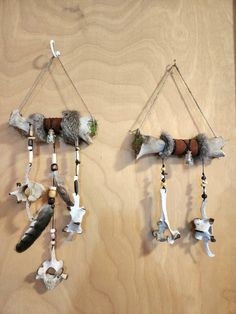 two wall hangings made out of wood with feathers and other things on them that are attached to the wall