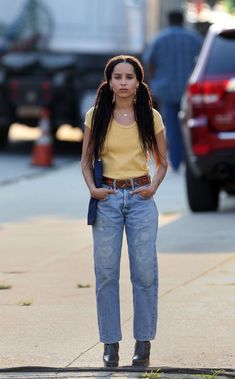 a woman standing on the sidewalk with her hands in her pockets