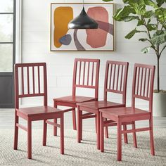 four red chairs sitting on top of a rug next to a potted green plant