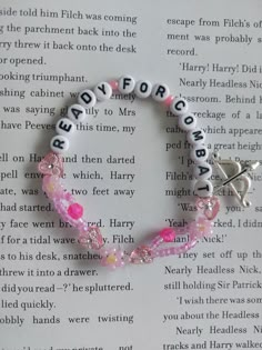 a book page with a pink and white beaded bracelet