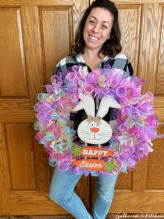 a woman standing in front of a door holding a wreath with an easter bunny on it