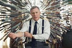 a man sitting on top of a chair with lots of knives hanging from it's back