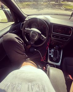 a person sitting in the driver's seat of a car with their feet on the steering wheel