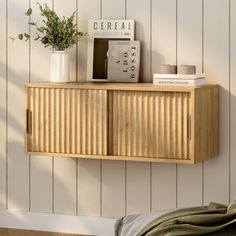 a wooden shelf with some books on top of it next to a wall mounted plant