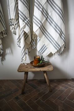 a wooden table topped with two towels and a bowl filled with oranges on top of it