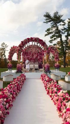 an outdoor ceremony setup with pink and white flowers on the aisle leading to the altar