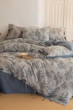 an unmade bed with blue and white comforter on top of it in a room