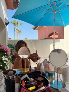 a woman sitting at a table holding a mirror and looking in it's reflection