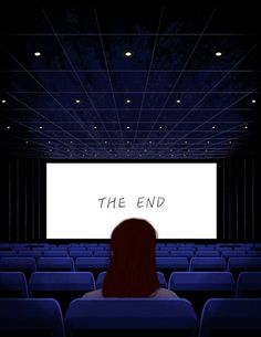 a woman is sitting in an empty theater watching the movie at night with her back turned to the camera