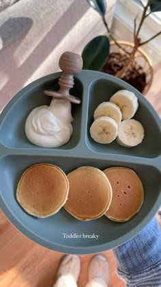 a person holding a plate with pancakes and bananas on it