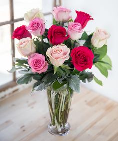 a glass vase filled with pink and red roses