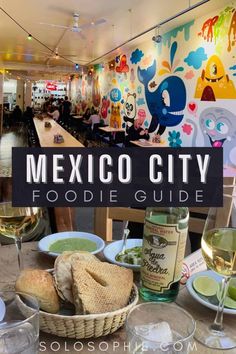 the mexican city foodie guide is displayed in front of a table with wine glasses and plates