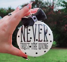 a hand holding a button with the words never trust the living on it in black and white