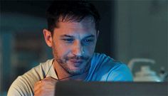 a man sitting in front of a laptop computer looking at the screen while wearing headphones