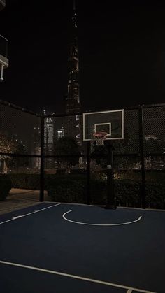 an outdoor basketball court at night with the city in the background