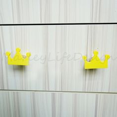 two yellow paper crowns are hanging on the wall