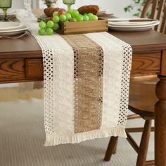 the table is set with plates and bowls of fruit on it, along with a white runner