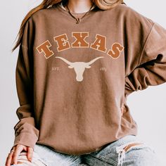 This Texas Longhorns crewneck sweatshirt is perfect for any University of Texas fan. It exudes school spirit and is great for wearing to games or casual outings. The relaxed fit and lightweight fabric make it comfortable for everyday wear. This runs true to size, so size up for a looser, oversized fit (my personal favorite).  Product Features - 100% ring-spun cotton - 1x1 ribbed cuffs and bottom hem for a well-fitted garment - Shoulder and neck tape for added stability - Without side seams for a more attractive look - Light fabric and sewn-in twill label Care instructions - Machine wash: cold (max 30C or 90F) - Do not bleach - Tumble dry: low heat - Iron, steam, or dry: low heat - Do not dry clean Print Quality:  I use a production partner, so all my products are printed professionally. I Texas Longhorns Shirts Vinyl, Texas Crewneck Sweatshirt, Texas Tech Crewneck, Texas Longhorns Sweatshirt, Texas Longhorn Tshirt, Football Vintage, Texas Longhorn, Comfort Colors Sweatshirt, Texas Longhorns