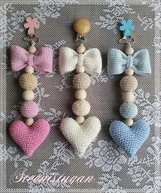 four small crocheted hearts with wooden beads and bows are arranged on a lace doily