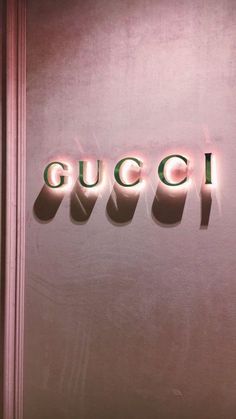 the word gucci is lit up in front of a pink wall