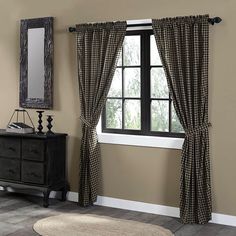 a room with a mirror, dresser and window curtain in the corner that has a plaid pattern on it