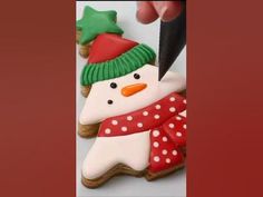 a decorated cookie with a snowman on it being cut into pieces by a knife