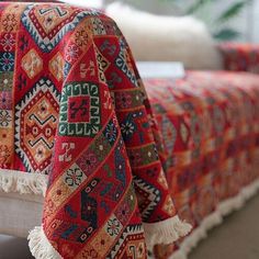 a bed covered in a colorful blanket next to a window