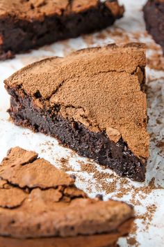 a piece of chocolate cake sitting on top of a white table next to some cookies