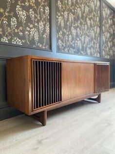 a wooden cabinet sitting on top of a hard wood floor next to a blue wall