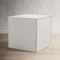 a white box sitting on top of a hard wood floor next to a gray wall