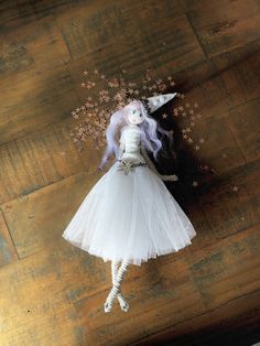 a doll is laying on the floor with flowers in it's hair and wearing a white dress