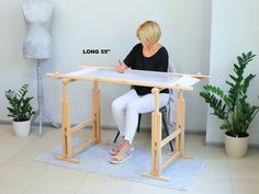 a woman sitting at a table with a piece of wood on top of it and writing