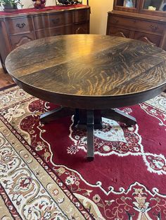 a round wooden table sitting on top of a red rug