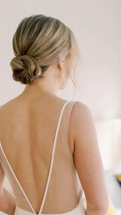 the back of a woman's dress with her hair in a low pony tail