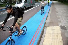 two bicyclists are riding down the bike path