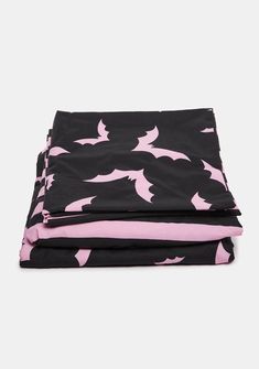 a black and pink bed spread with shark print on the bottom, two sheets are folded up