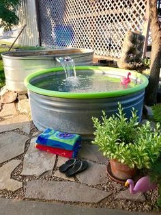 a water fountain in the middle of a yard with potted plants and sandals on the ground