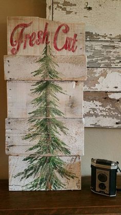 a wooden sign that says fresh cut with a pine tree painted on it and an old camera next to it