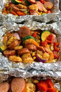 two trays filled with different types of food on tin foil covered in aluminum foil