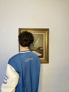 a man standing in front of a painting on the wall with his back to the camera